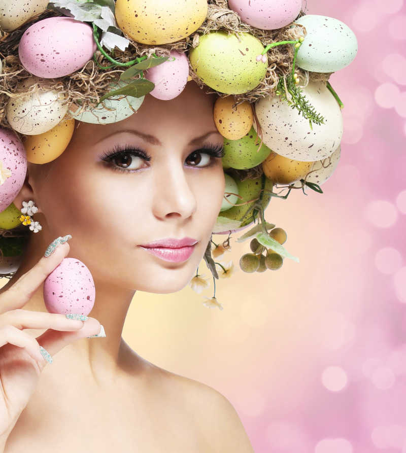 粉色背景下头戴复活节彩蛋装饰手拿彩蛋的性感女人