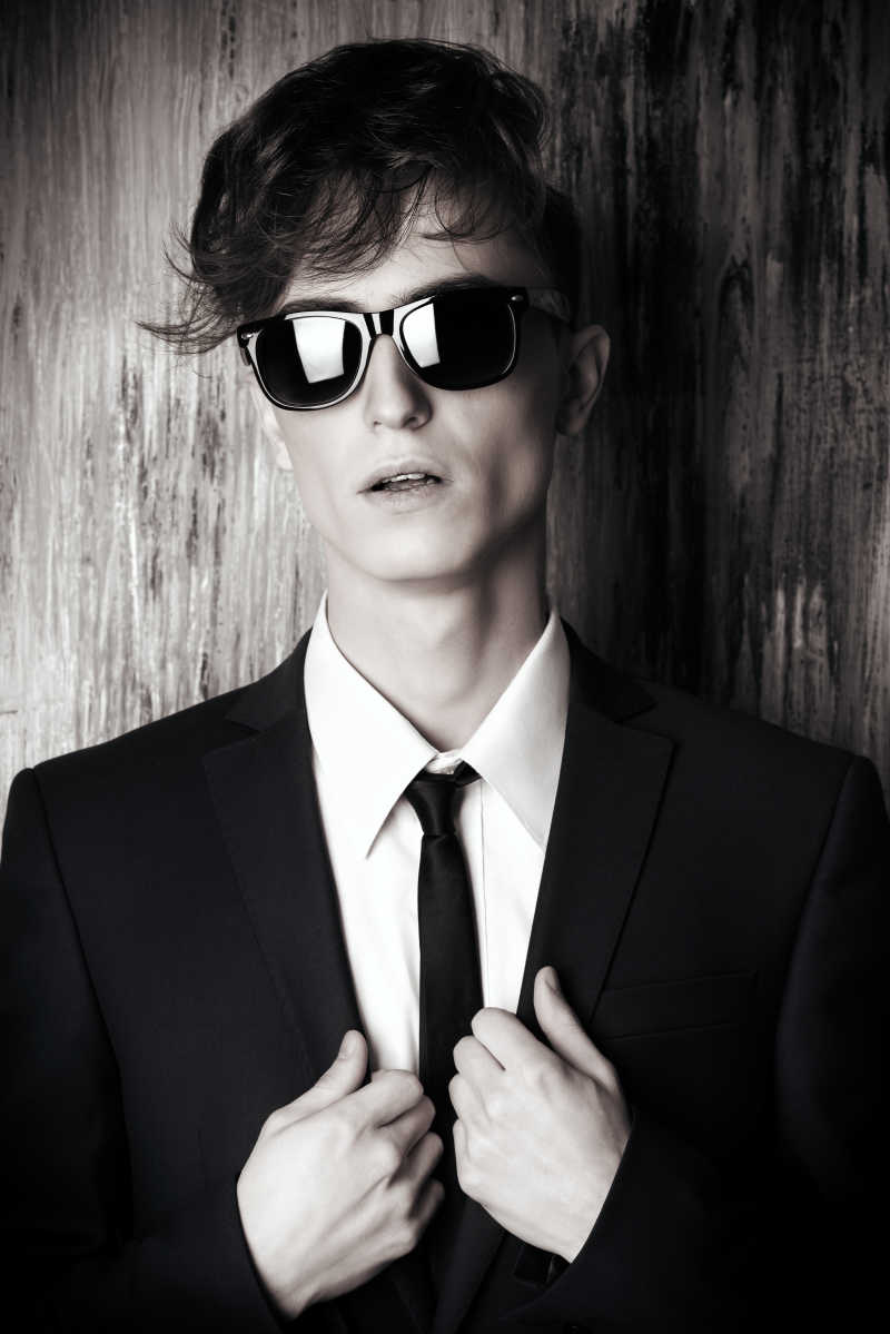 一个穿着优雅套装和太阳镜的时尚年轻人