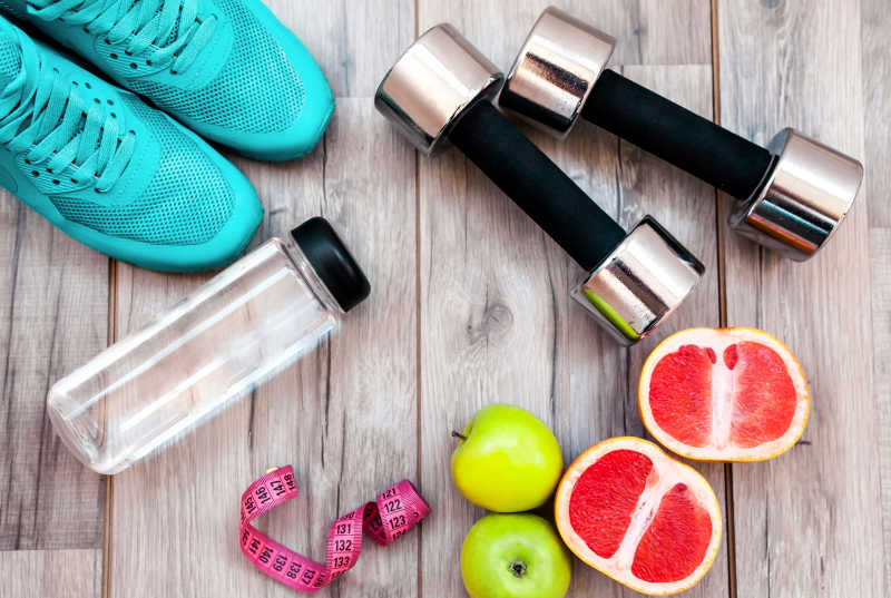 木桌上的运动健身器材和水果以及皮尺