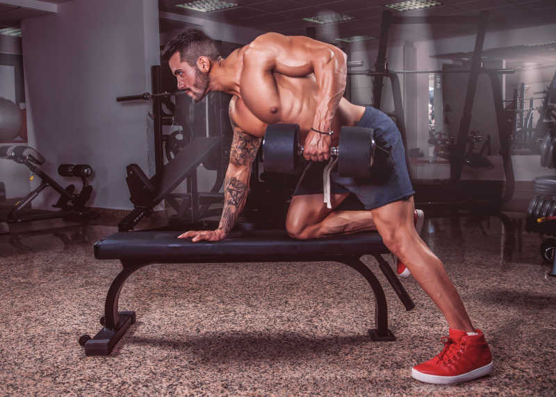 在健身房用哑铃锻炼的肌肉男