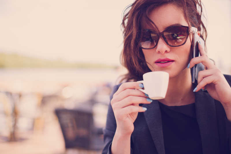 一边用手机聊天一边喝咖啡的漂亮女孩