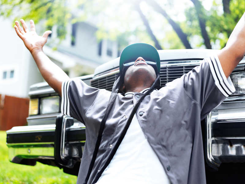 年轻的黑人在汽车前举高双手