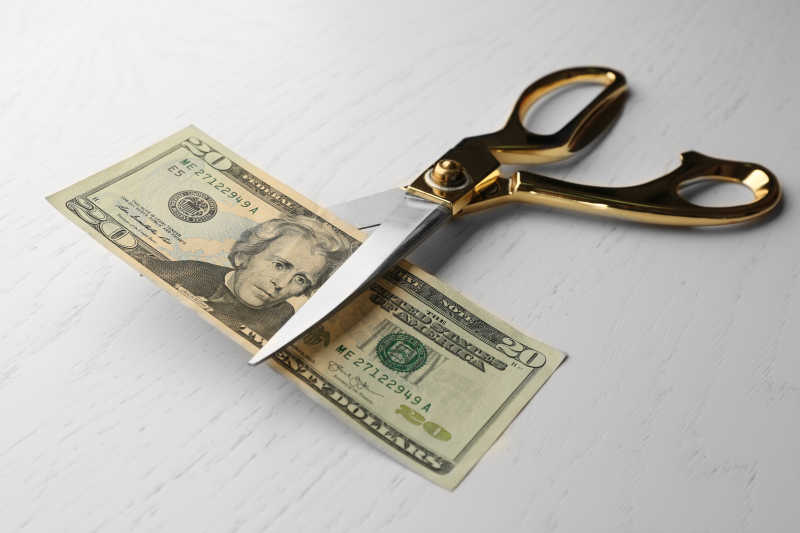 剪刀在桌上切美元钞票