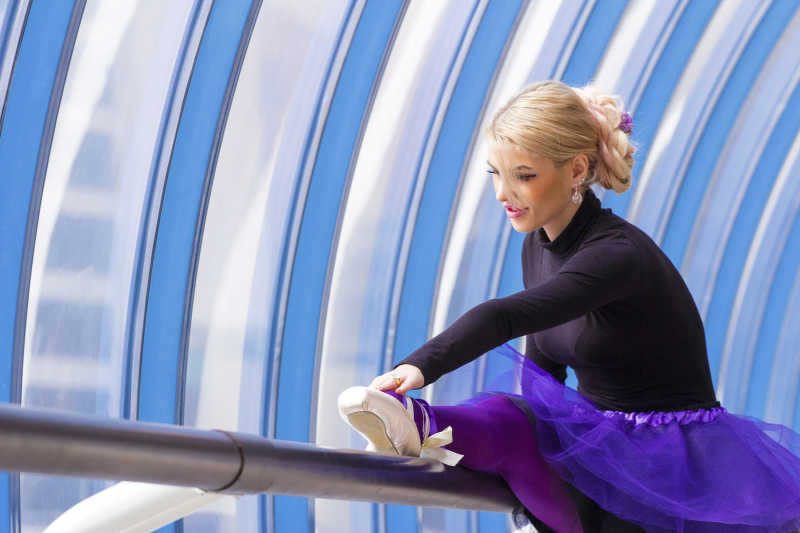 在栏杆上压腿的女芭蕾舞者