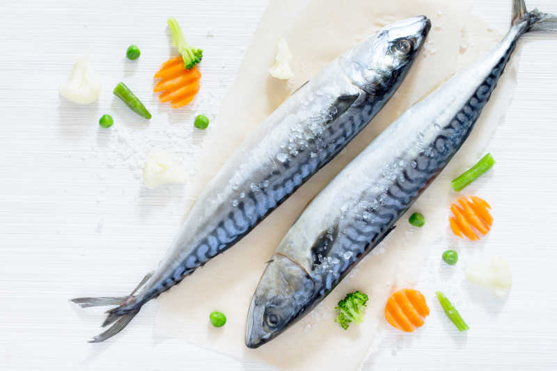 木质背景下新鲜的两条鱼和有机配菜