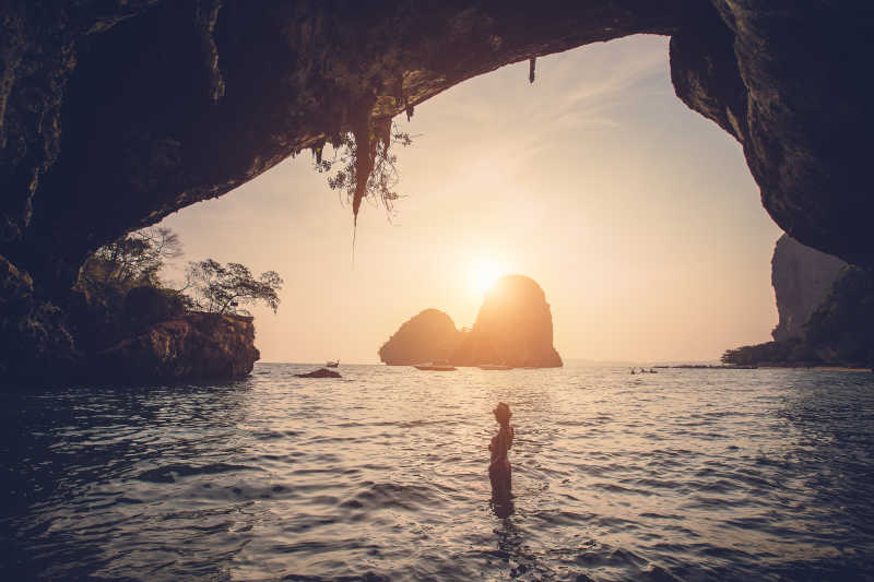 夕阳下海滩上山洞口的美女剪影