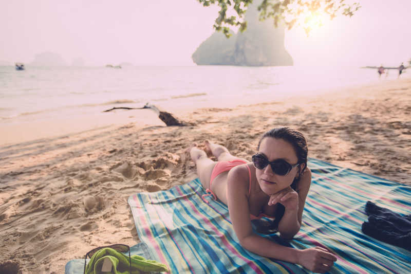 日落时分趴在海滩上的比基尼美女