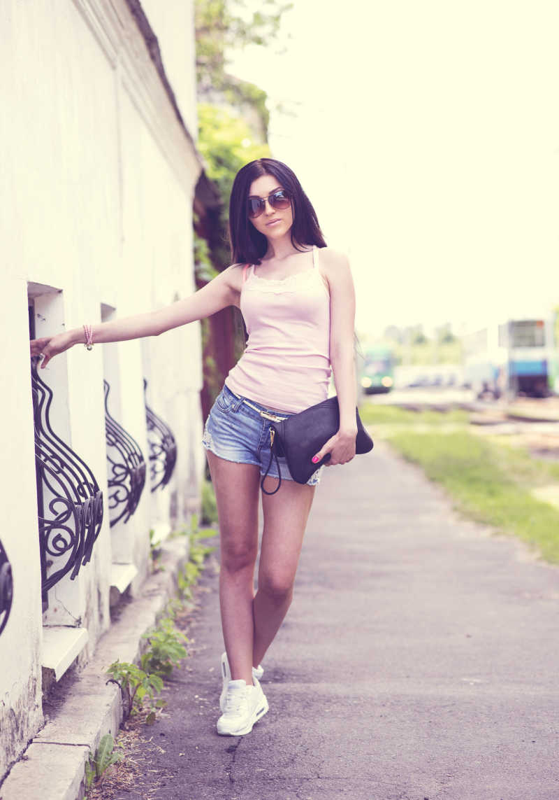 在街上一只手拉着栏杆的美丽女孩