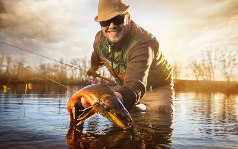 钓鱼者拿着自己的钓上来的鱼