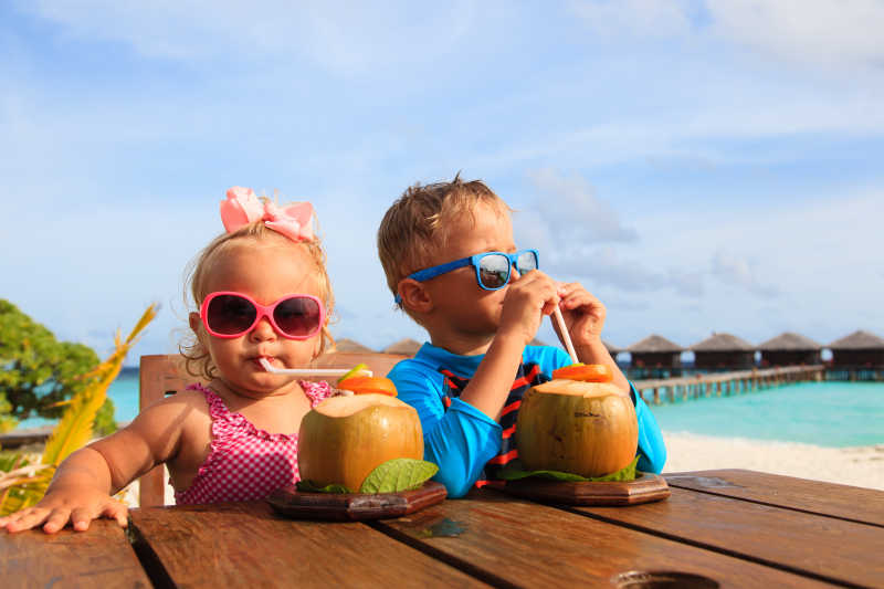 小男孩和小女孩在木板上喝椰子汁