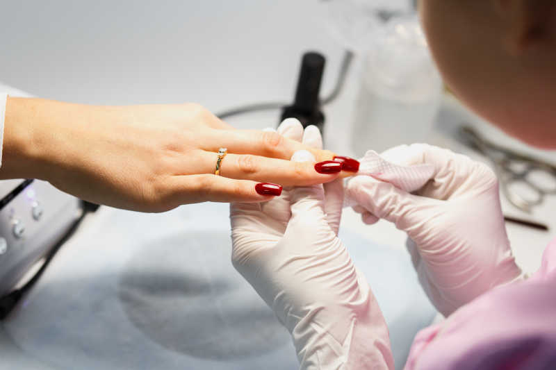 为顾客擦拭多涂的指甲油