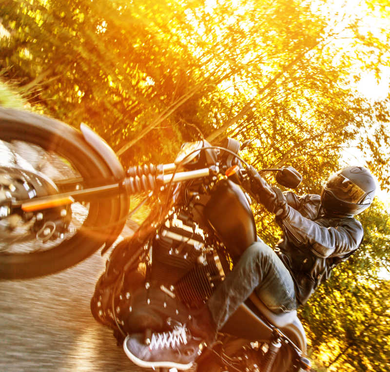 日出时森林路上的骑摩托青年