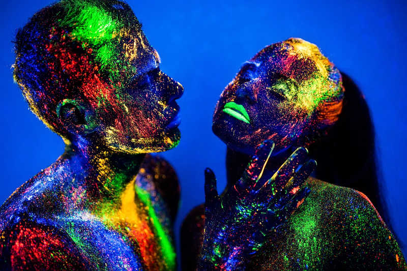 身上涂着彩色荧光粉的恋人在迪斯科舞厅跳舞