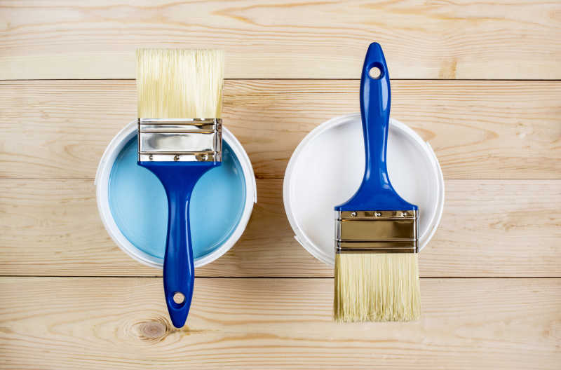 蓝色和白色油漆罐上的两个毛刷