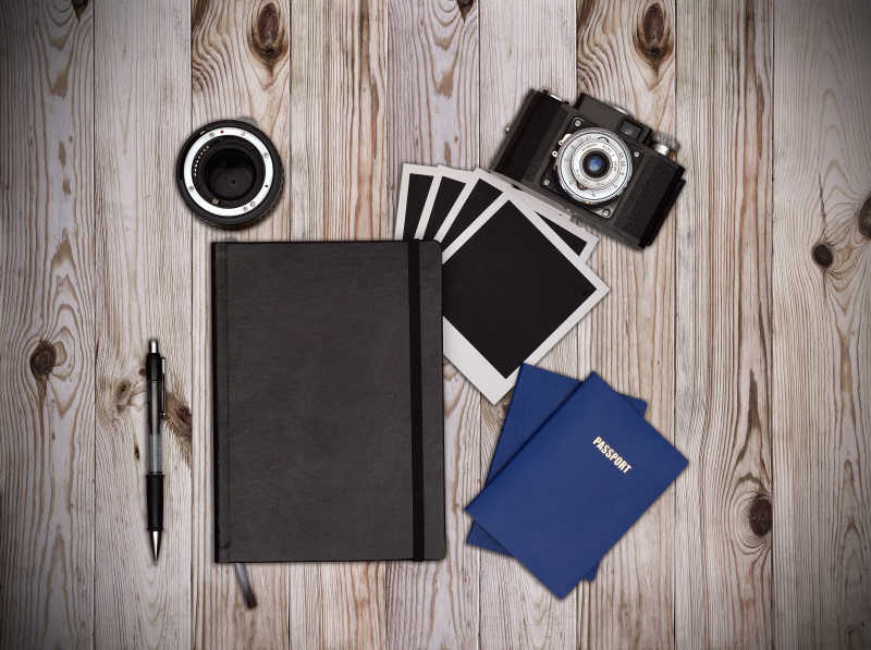 木桌上的笔记本相机和照片