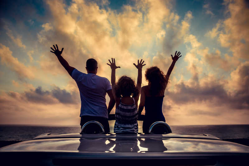 海滩上举高双手放松的家庭剪影