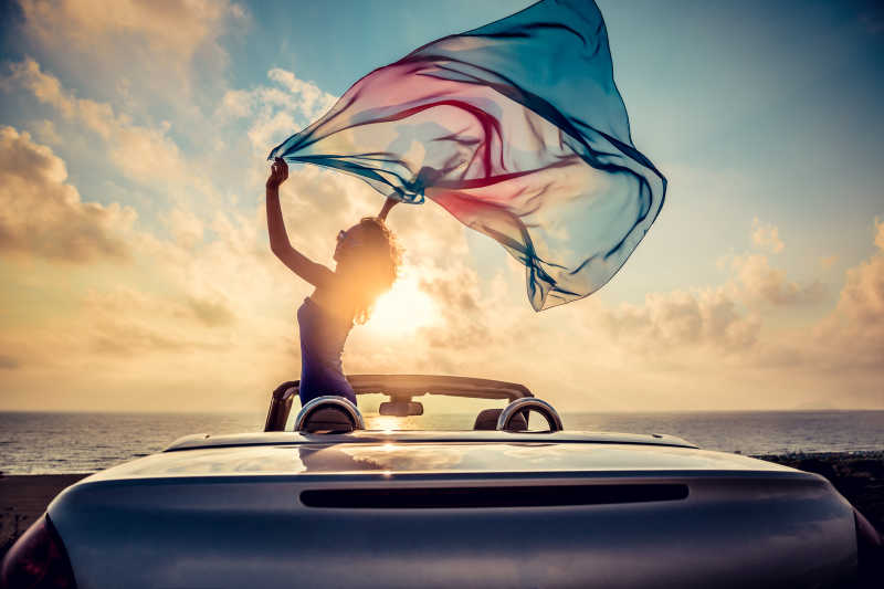 沙滩上放松的年轻美女扬起纱巾剪影