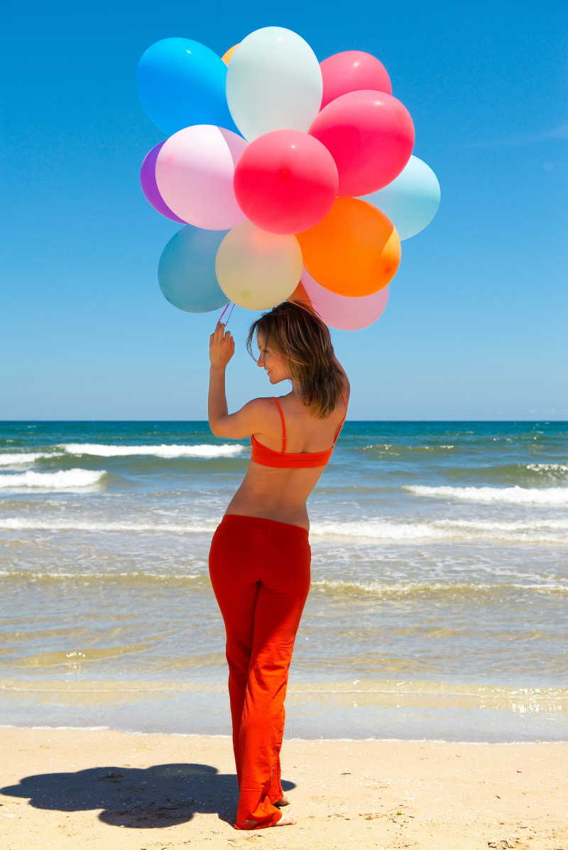海滩边拿着气球的红衣女人