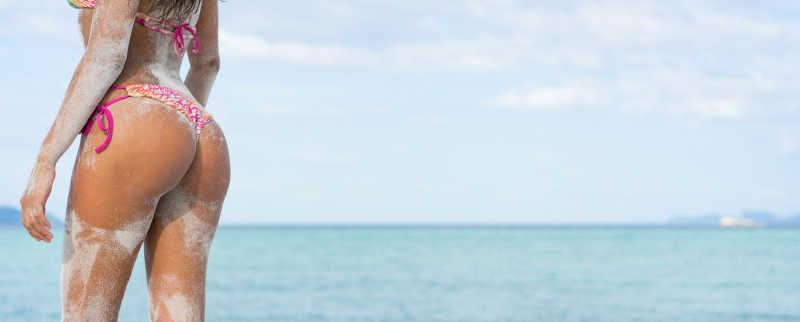 蓝色大海背景下穿比基尼的美女臀部