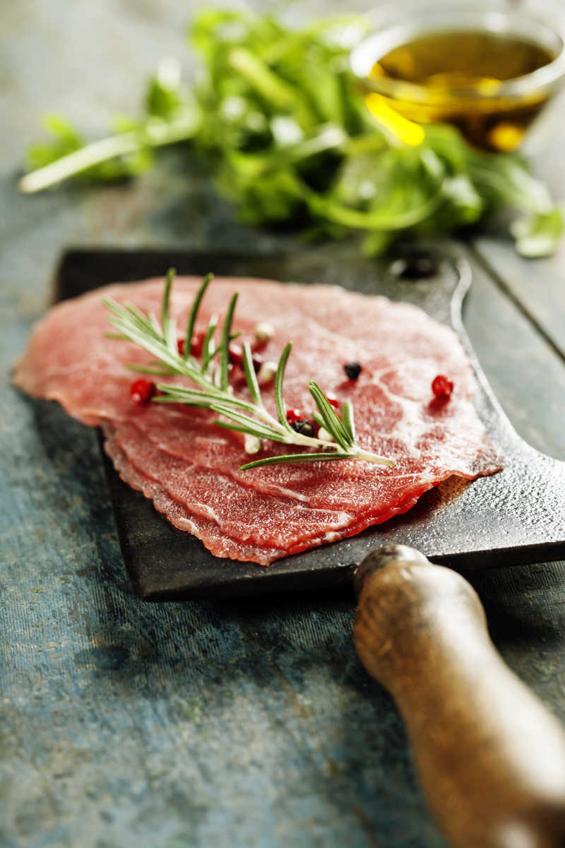 在黑暗的背景下的老式的切肉刀和生牛排