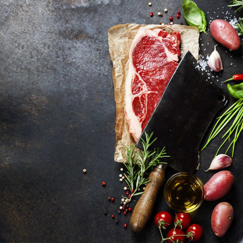 黑色的砧板上的老式切肉刀和牛肉