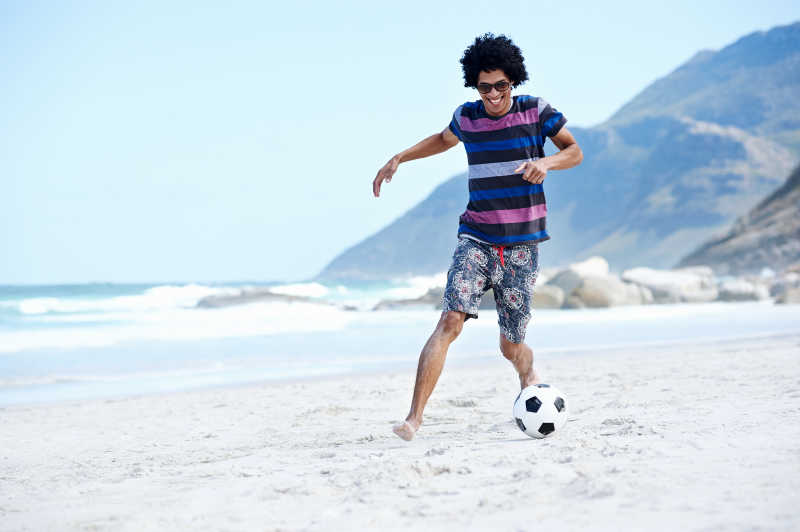男孩在沙滩上踢球