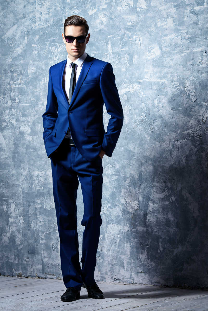 一个穿着优雅的古典西装和太阳镜的时尚英俊年轻男子