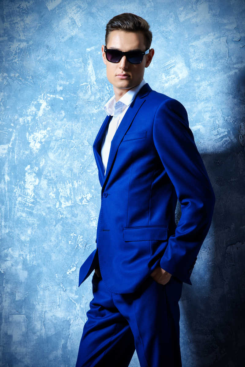 时尚的年轻男子穿着优雅的经典西装和太阳镜