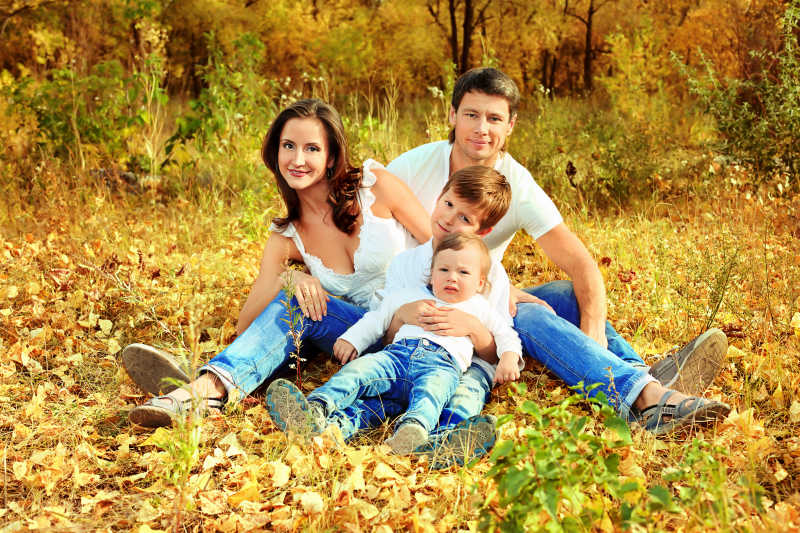 快乐的家庭在秋天的公园里休息