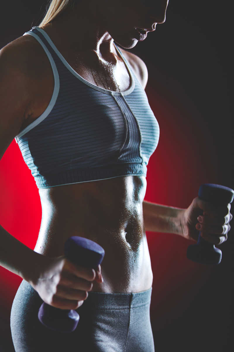 拿着哑铃运动出汗的苗条女子