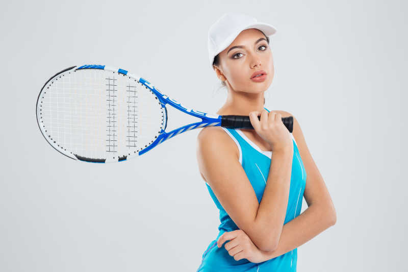 一个美丽的女网球运动员在白色背景下拿着网球拍