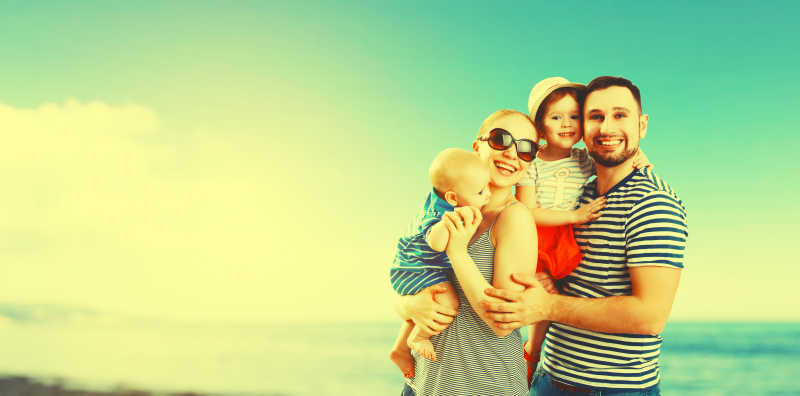 海滩上快乐的父亲母亲和两个孩子