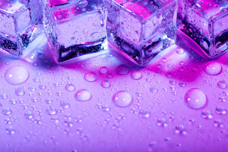 粉色背景下冰块和欢快明亮的水珠
