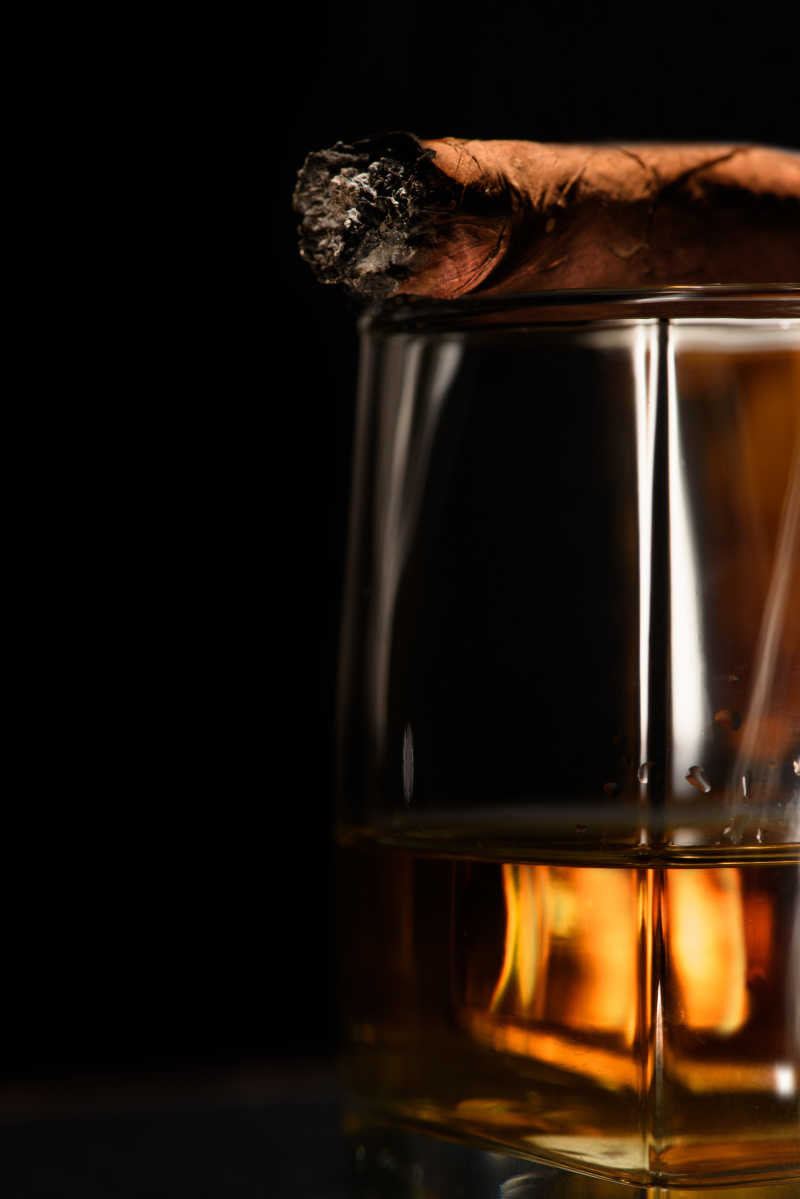 黑暗的背景下干邑雪茄和威士忌酒杯