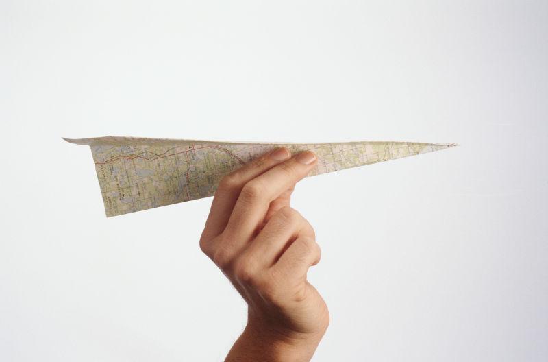 白色背景下男人手里拿着的地图纸飞机