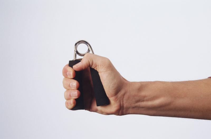 白色背景下男人手里的握力器