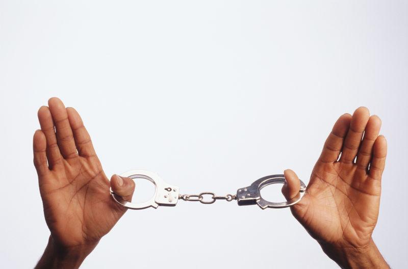 白色背景下一双手拿着的手铐