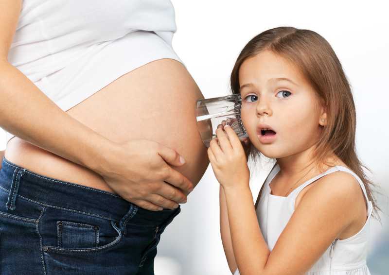 小女孩听着孕妇的肚子表示很惊讶