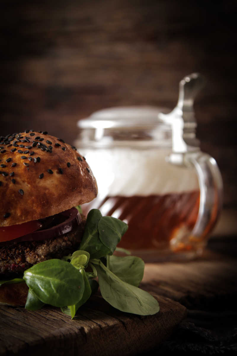 在木制的背景上自制素食汉堡和啤酒快餐