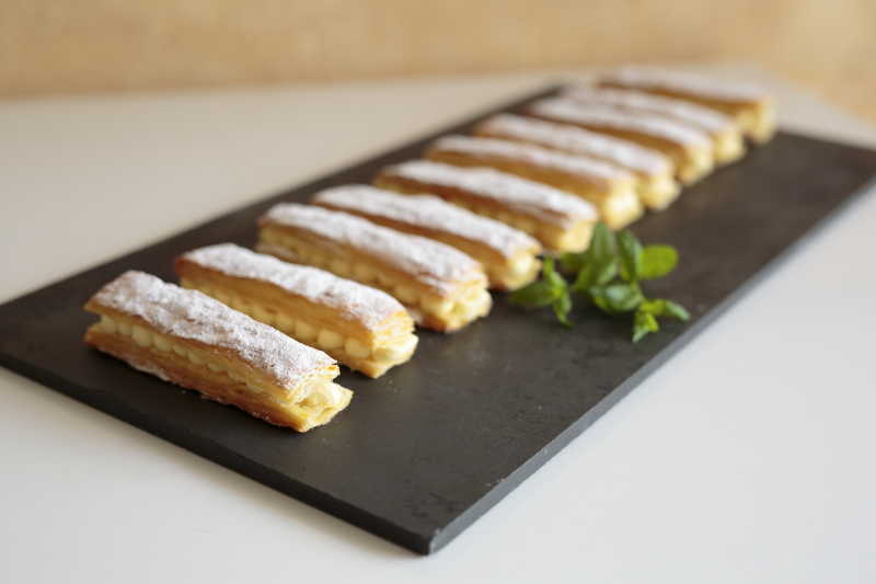 白色背景下黑色盘子里摆放整齐的奶油馅饼