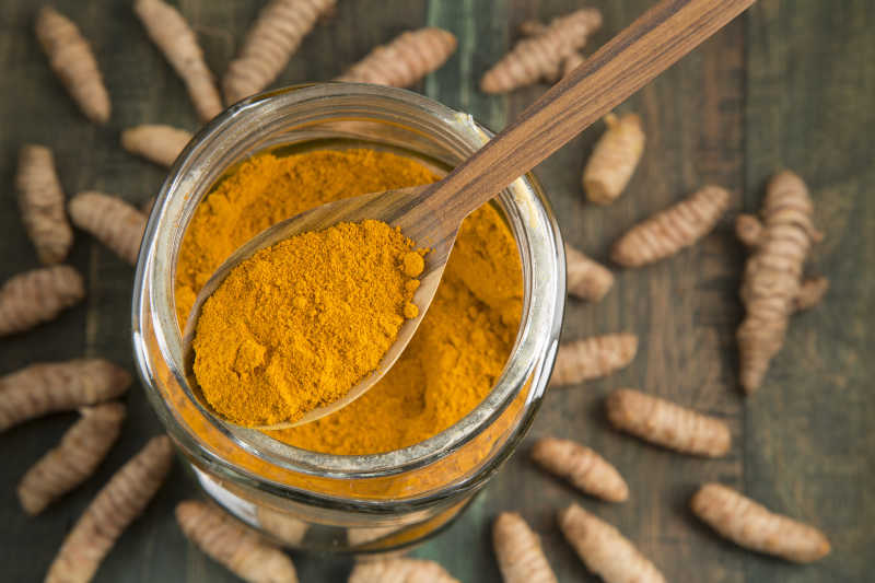 姜黄根和的玻璃罐里的姜黄粉