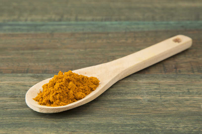 木板上的木勺里的姜黄粉