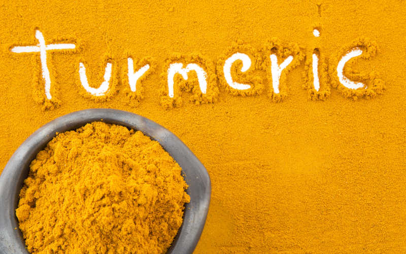 姜黄粉背景下装满姜黄粉的碗