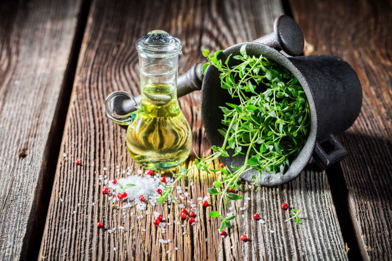 木制背景下的盐胡椒和百里香