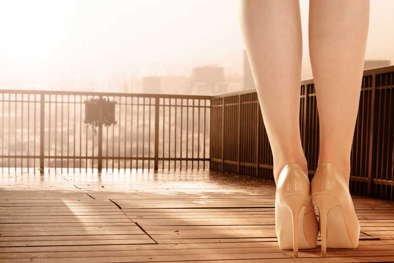 木制地板上穿着高跟鞋的美女的腿
