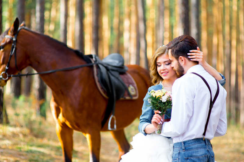 树林里面棕色马旁边的新郎新娘