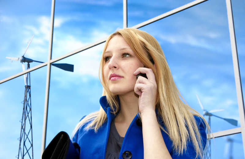 在风力发电机附近接电话的女商人