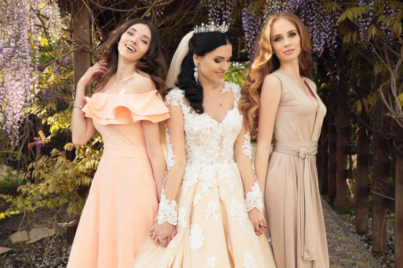 花园中摆姿势的伴娘和新娘