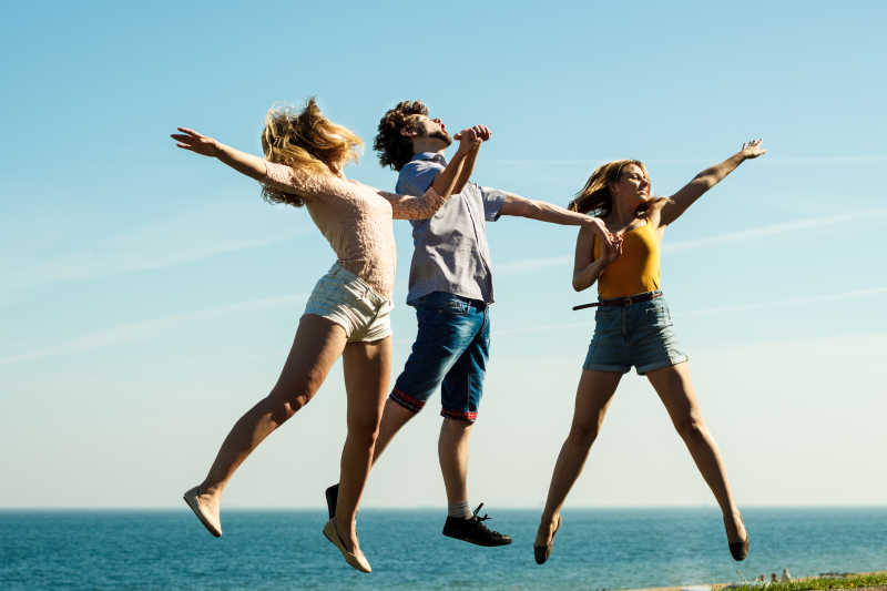 手牵手跳起来的两个男孩和一个女孩