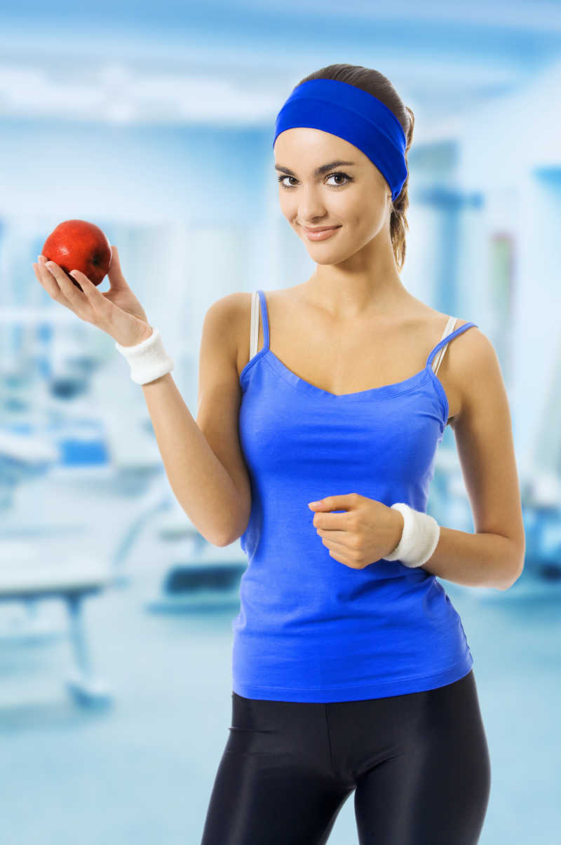 穿着运动装的女人拿着苹果